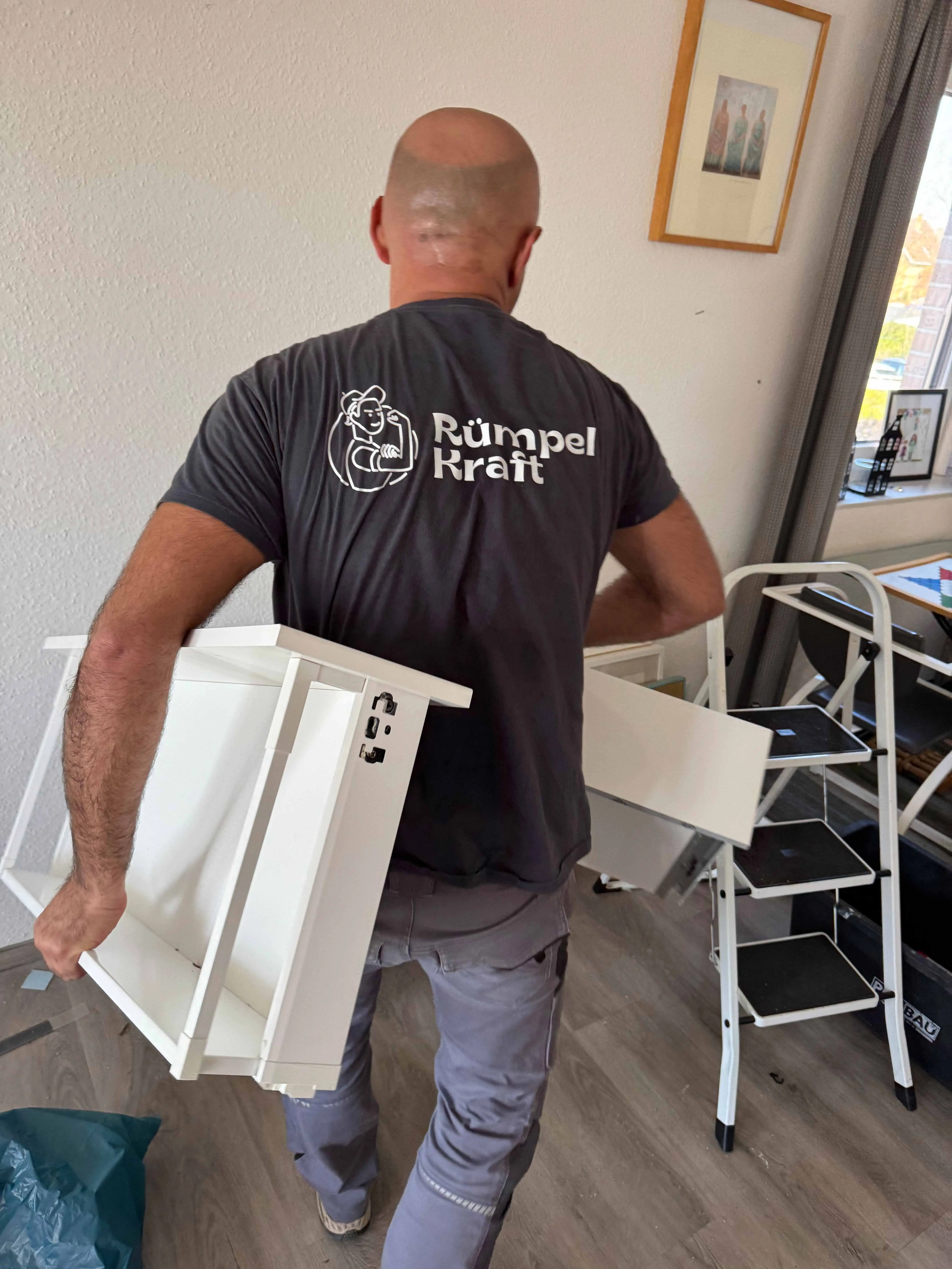 Mitarbeiter von Rümpelkraft trägt Möbel aus einer Wohnung